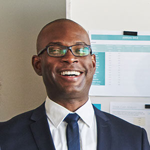 A man in a suit and tie smiling for the camera.