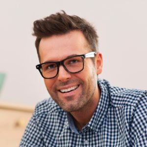 A man with glasses smiling for the camera.