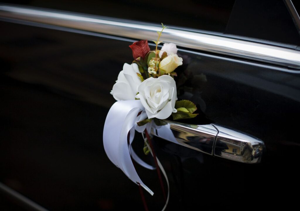 A bouquet of flowers tied to the side of a car door.